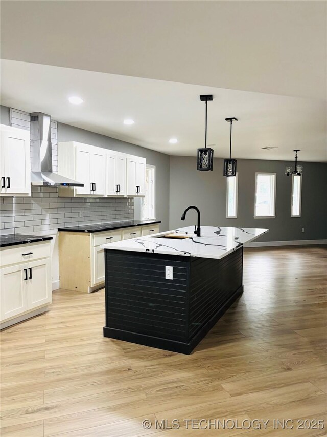3622 S 82nd E Ave, Tulsa, OK 74145 - kitchen featuring wall chimney exhaust hood, light wood-style floors, tasteful backsplash, decorative light fixtures, and white cabinets