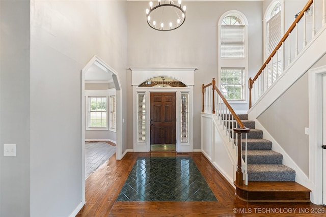 10295 E Rose Glen Dr, Claremore, OK 74019 - foyer entrance featuring a high ceiling, wood finished floors, stairs, arched walkways, and a chandelier