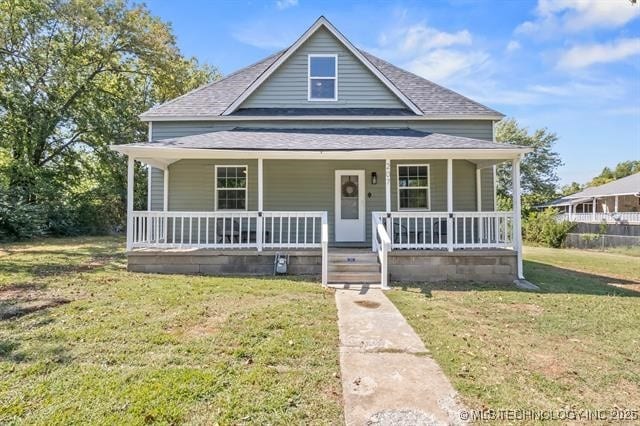 207 N Graham Ave, Wagoner, OK 74467 - view of front of house featuring a porch, roof with shingles, and a front yard