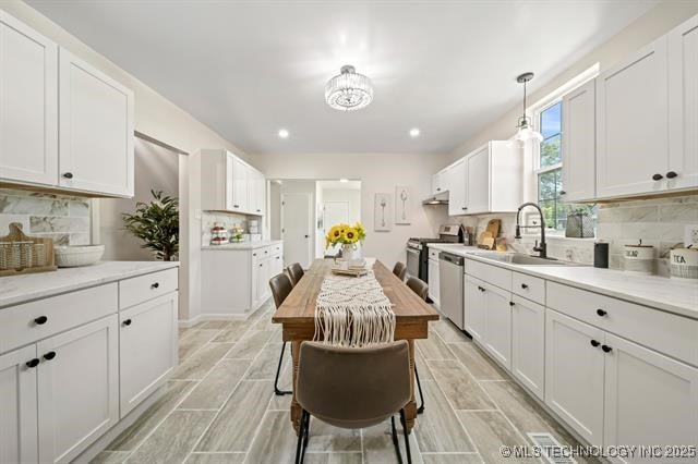 207 N Graham Ave, Wagoner, OK 74467 - kitchen featuring appliances with stainless steel finishes, white cabinetry, decorative backsplash, and recessed lighting