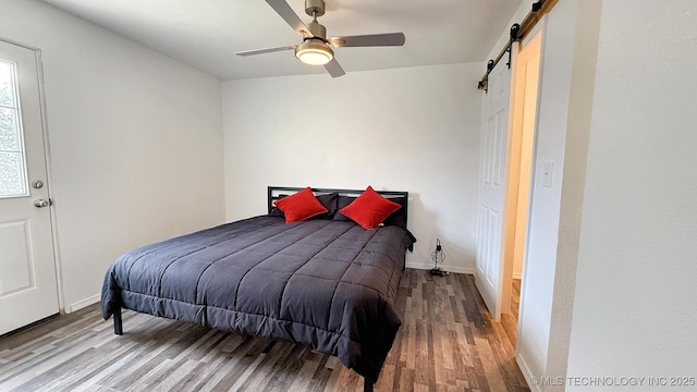 102 N Ash Ave, Tahlequah, OK 74464 - bedroom featuring a barn door, wood finished floors, and ceiling fan