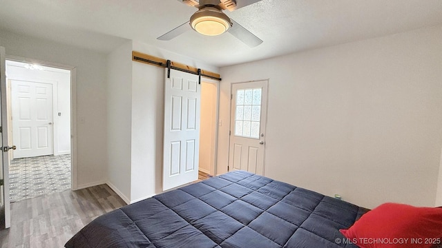 102 N Ash Ave, Tahlequah, OK 74464 - bedroom with a barn door, wood finished floors, and ceiling fan