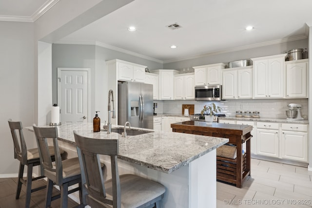 701 E 119th St, Jenks, OK 74037 - kitchen featuring appliances with stainless steel finishes, a breakfast bar, white cabinets, tasteful backsplash, and light stone counters