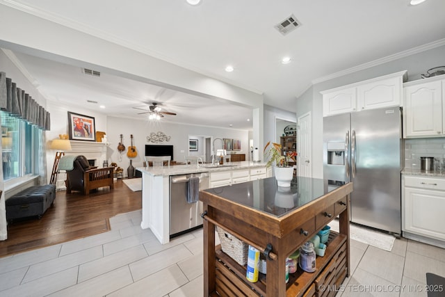701 E 119th St, Jenks, OK 74037 - kitchen featuring appliances with stainless steel finishes, open floor plan, a peninsula, crown molding, and white cabinetry