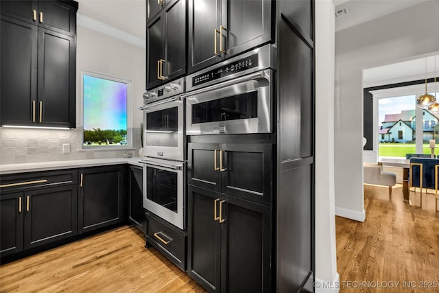 17076 S 31st E Ave, Mounds, OK 74047 - kitchen featuring dark cabinets, appliances with stainless steel finishes, light wood-style floors, and decorative backsplash