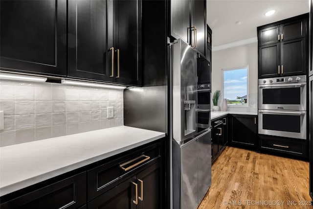 17076 S 31st E Ave, Mounds, OK 74047 - kitchen featuring appliances with stainless steel finishes, dark cabinets, decorative backsplash, light wood-type flooring, and ornamental molding