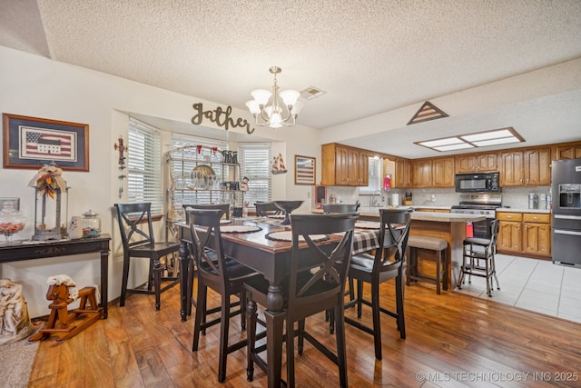 9901 N 107th E Ave, Owasso, OK 74055 - dining space featuring a textured ceiling, a chandelier, and light wood-type flooring