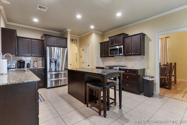 2610 E 139th St S, Jenks, OK 74008 - kitchen featuring stainless steel appliances, backsplash, light stone countertops, dark brown cabinetry, and ornamental molding