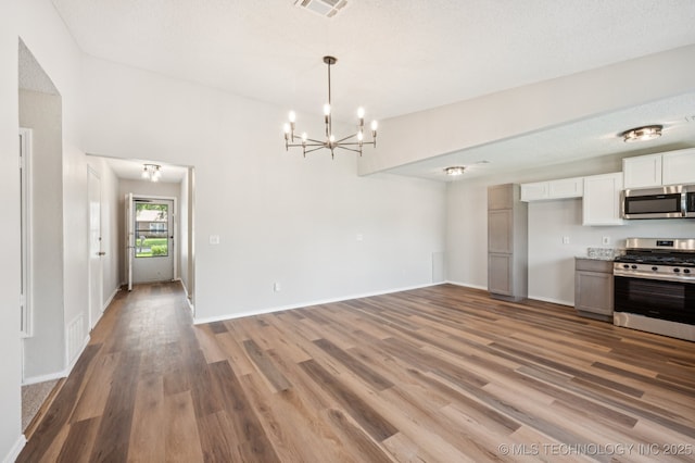 208 183rd E Ave, Tulsa, OK 74108 - kitchen with appliances with stainless steel finishes, light wood finished floors, a chandelier, white cabinetry, and open floor plan