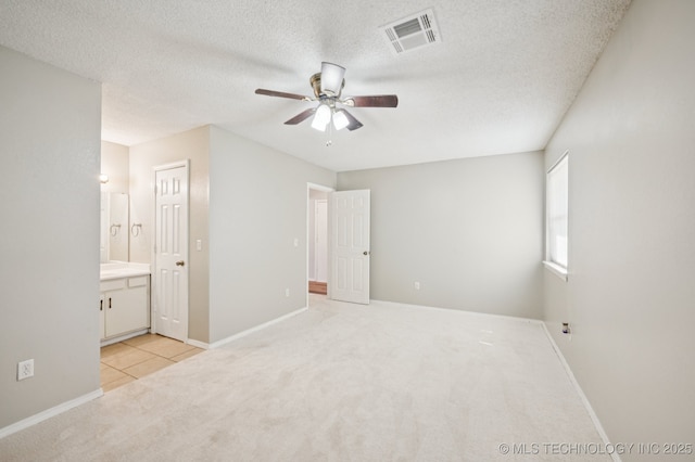 208 183rd E Ave, Tulsa, OK 74108 - unfurnished bedroom with light carpet, a textured ceiling, ensuite bath, ceiling fan, and light tile patterned floors
