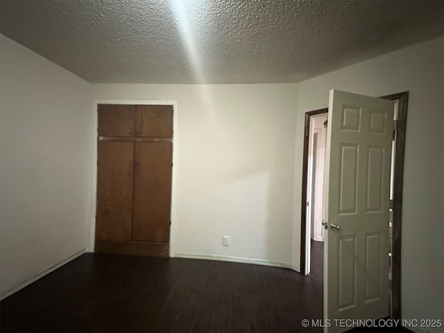 1208 S 9th, Mcalester, OK 74501 - unfurnished bedroom with dark wood-style floors, a closet, and a textured ceiling