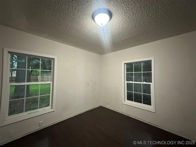 1208 S 9th, Mcalester, OK 74501 - unfurnished room featuring a textured ceiling and dark wood-type flooring