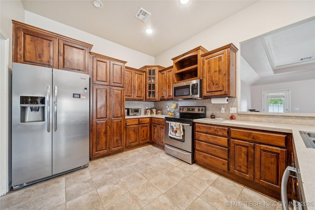 7440 E Indianola St, Broken Arrow, OK 74014 - kitchen with appliances with stainless steel finishes, brown cabinets, tasteful backsplash, light countertops, and glass insert cabinets
