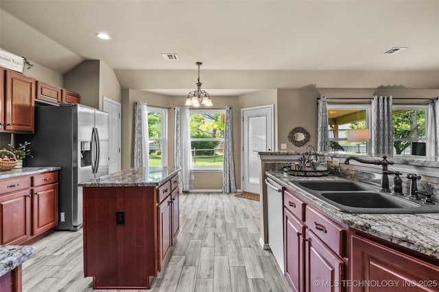 14908 E 88th St, Owasso, OK 74055 - kitchen featuring appliances with stainless steel finishes, wood finish floors, a kitchen island, pendant lighting, and a chandelier