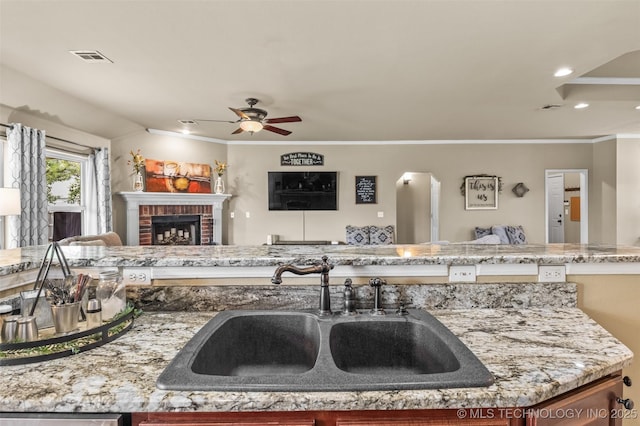 14908 E 88th St, Owasso, OK 74055 - kitchen featuring open floor plan, ceiling fan, a brick fireplace, crown molding, and light stone countertops