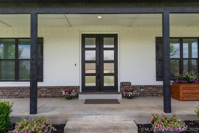 19021 E Chokeberry St, Owasso, OK 74055 - view of exterior entry with covered porch, brick siding, and french doors