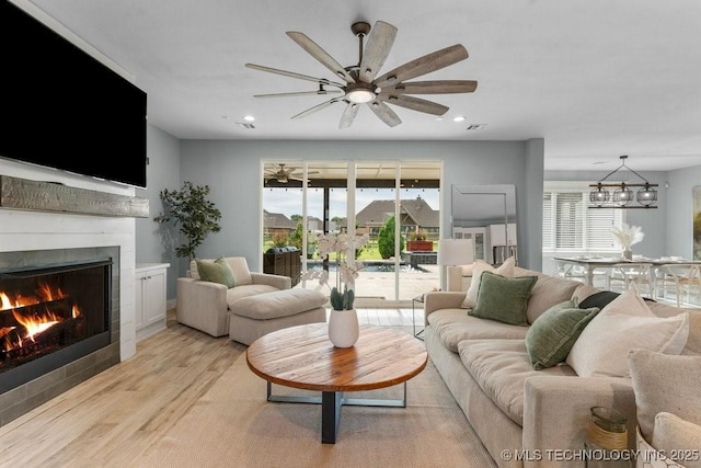 19021 E Chokeberry St, Owasso, OK 74055 - living area with a warm lit fireplace, light wood finished floors, plenty of natural light, ceiling fan, and recessed lighting