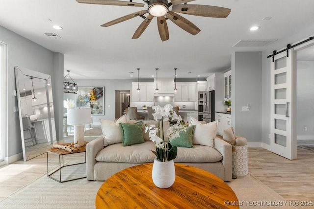 19021 E Chokeberry St, Owasso, OK 74055 - living room featuring a barn door, recessed lighting, ceiling fan, and light wood-style flooring