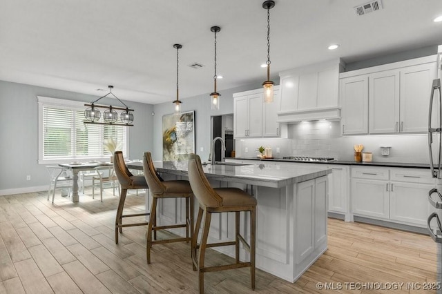 19021 E Chokeberry St, Owasso, OK 74055 - kitchen with light wood finished floors, stainless steel gas cooktop, decorative backsplash, white cabinets, and recessed lighting