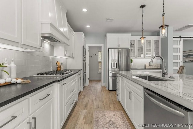 19021 E Chokeberry St, Owasso, OK 74055 - kitchen with stainless steel appliances, a barn door, white cabinets, backsplash, and recessed lighting