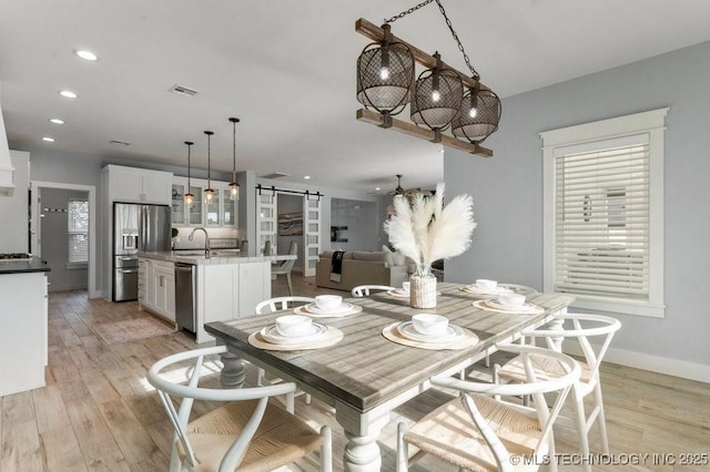 19021 E Chokeberry St, Owasso, OK 74055 - dining area featuring a barn door, light wood-type flooring, and recessed lighting