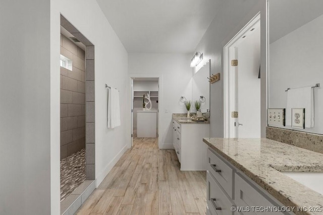 19021 E Chokeberry St, Owasso, OK 74055 - bathroom with two vanities, wood finished floors, a walk in shower, and a spacious closet