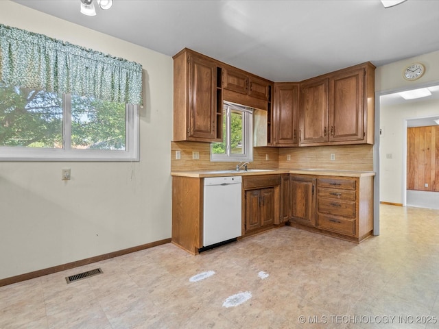 123 S Madison Blvd, Bartlesville, OK 74006 - kitchen featuring white dishwasher, light countertops, decorative backsplash, and brown cabinets