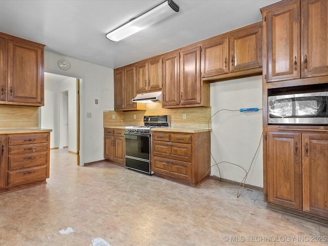 123 S Madison Blvd, Bartlesville, OK 74006 - kitchen featuring gas range, stainless steel microwave, brown cabinetry, and under cabinet range hood