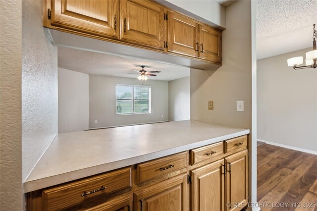 612 S 5th St, Eufaula, OK 74432 - kitchen with light countertops, a ceiling fan, dark wood-style flooring, a chandelier, and brown cabinets