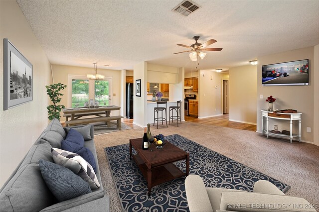612 S 5th St, Eufaula, OK 74432 - living room featuring a textured ceiling, light colored carpet, a ceiling fan, and a chandelier