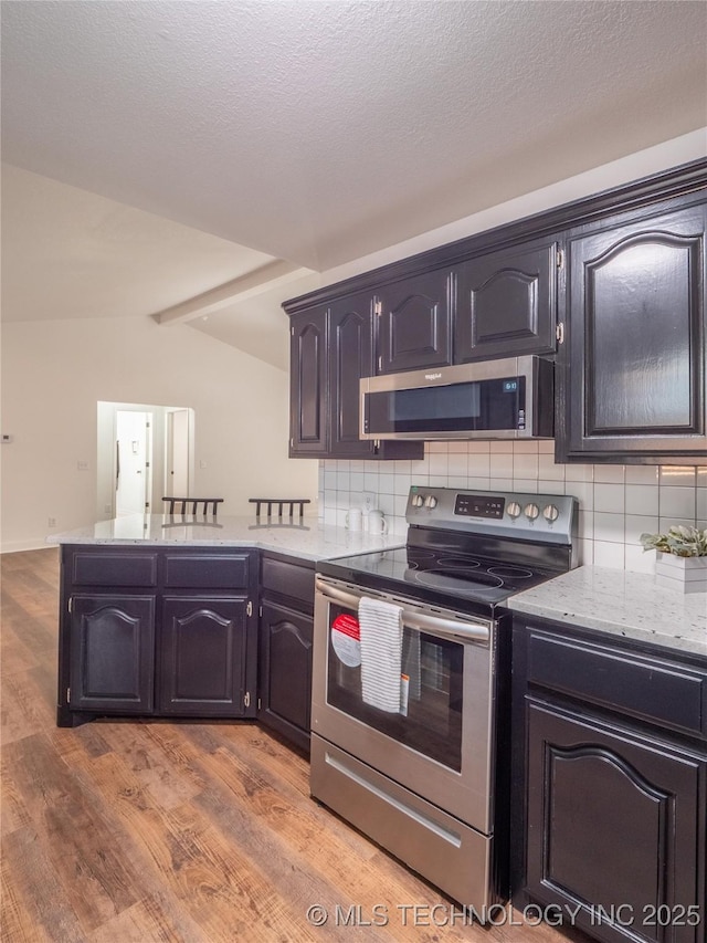 3404 N Birch, Mcalester, OK 74501 - kitchen with appliances with stainless steel finishes, decorative backsplash, a peninsula, light wood-style floors, and light stone countertops