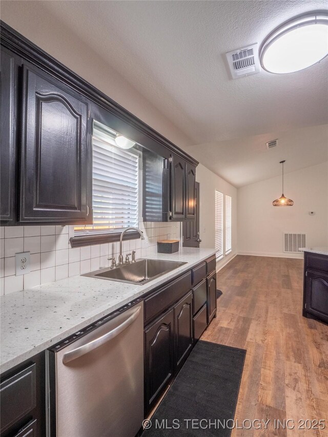 3404 N Birch, Mcalester, OK 74501 - kitchen with stainless steel dishwasher, vaulted ceiling, tasteful backsplash, wood finished floors, and decorative light fixtures