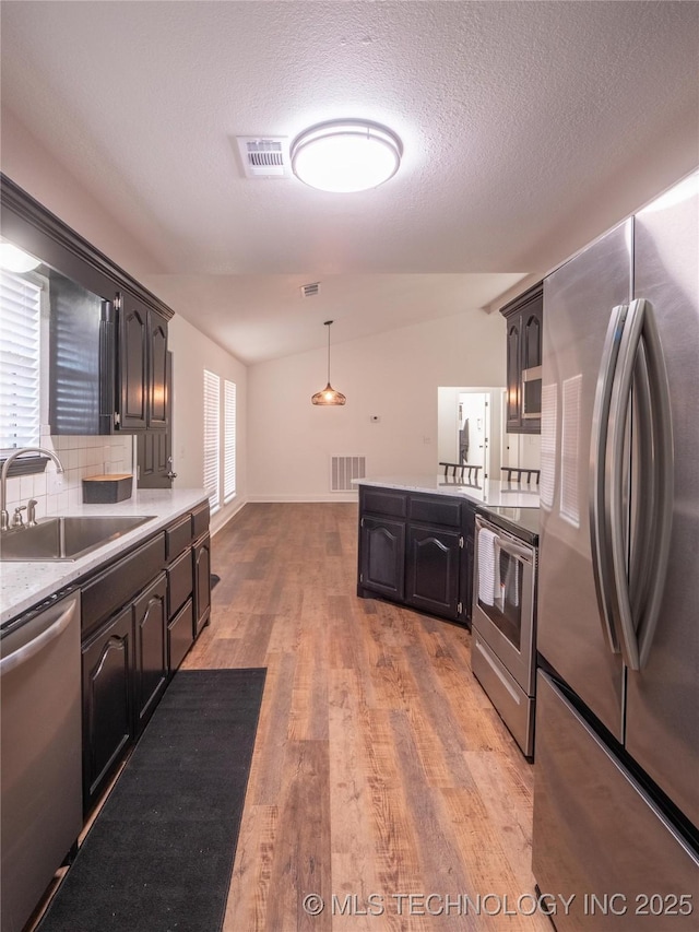 3404 N Birch, Mcalester, OK 74501 - kitchen featuring stainless steel appliances, vaulted ceiling, light wood-style flooring, light countertops, and decorative backsplash
