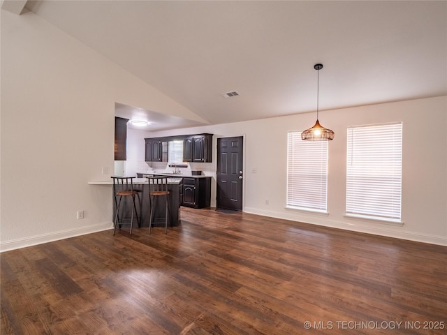 3404 N Birch, Mcalester, OK 74501 - kitchen featuring vaulted ceiling, a peninsula, dark wood-style flooring, a breakfast bar, and light countertops