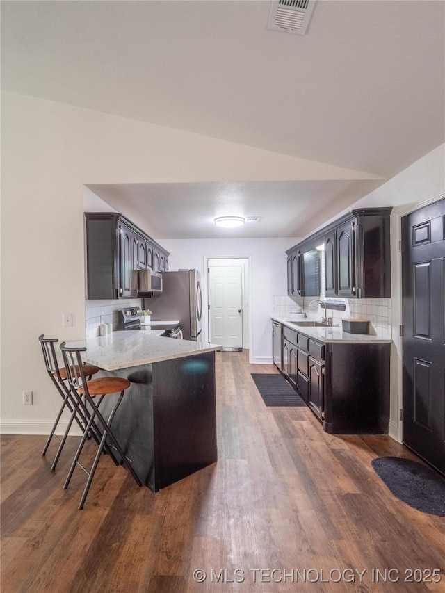 3404 N Birch, Mcalester, OK 74501 - kitchen featuring stainless steel appliances, a peninsula, dark wood finished floors, decorative backsplash, and a kitchen breakfast bar