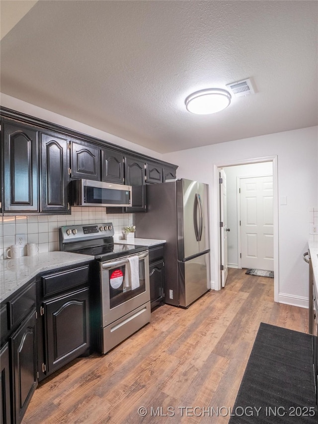 3404 N Birch, Mcalester, OK 74501 - kitchen featuring stainless steel appliances, tasteful backsplash, light wood finished floors, light stone countertops, and dark cabinets