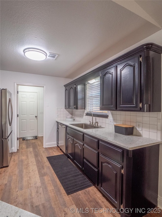 3404 N Birch, Mcalester, OK 74501 - kitchen featuring appliances with stainless steel finishes, backsplash, light wood-type flooring, a textured ceiling, and light stone counters
