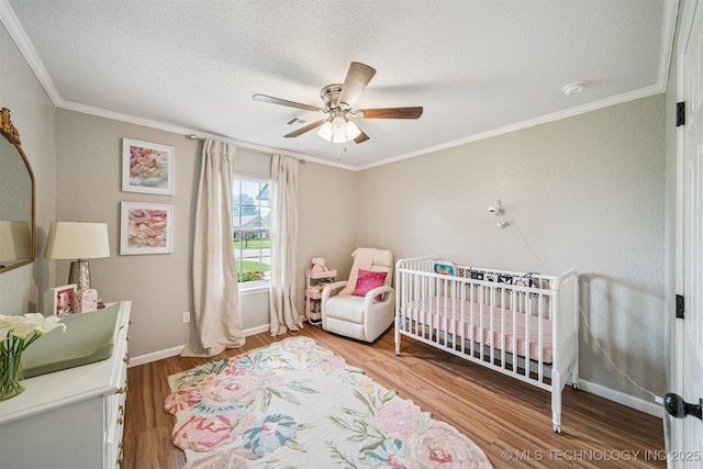 11017 E 98th St N, Owasso, OK 74055 - bedroom featuring wood finished floors, a nursery area, ornamental molding, a textured ceiling, and ceiling fan