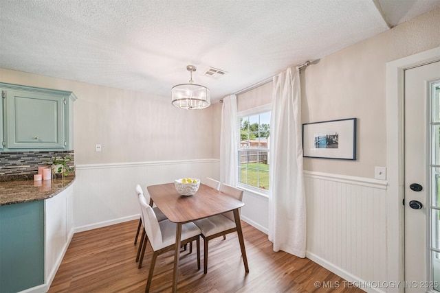 11017 E 98th St N, Owasso, OK 74055 - dining space with wood finished floors, wainscoting, a chandelier, and a textured ceiling
