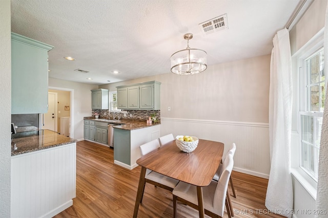 11017 E 98th St N, Owasso, OK 74055 - dining area with light wood-type flooring, a wainscoted wall, and a chandelier