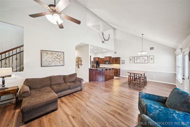 10220 N 119th E Ave, Owasso, OK 74055 - living room featuring ceiling fan, wood finished floors, a chandelier, high vaulted ceiling, and stairs