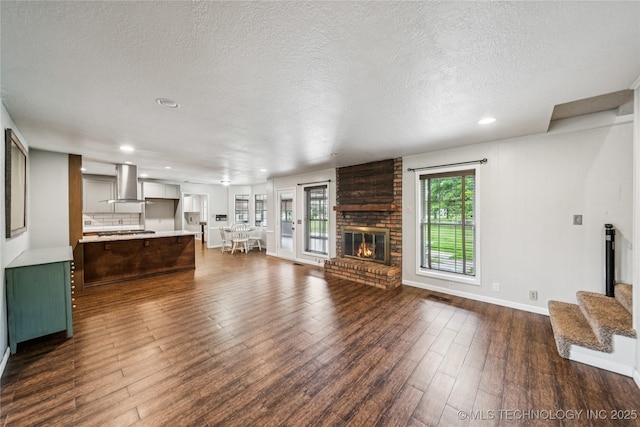 6103 S 223rd E Ave, Broken Arrow, OK 74014 - unfurnished living room featuring a fireplace, dark wood finished floors, recessed lighting, and a textured ceiling