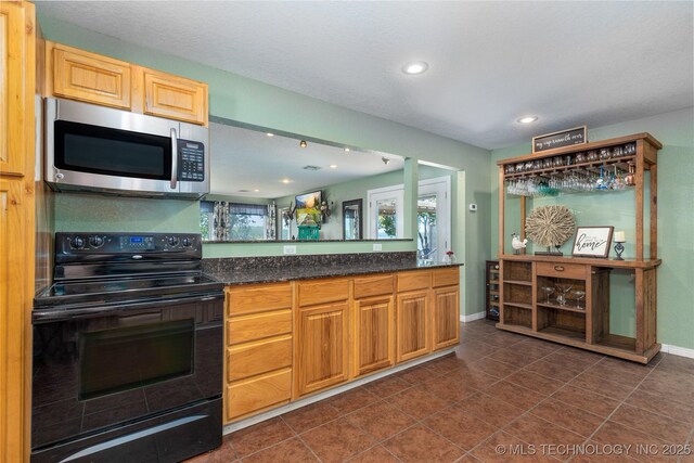 61112 E 310, Grove, OK 74344 - kitchen featuring black range with electric stovetop, stainless steel microwave, recessed lighting, dark tile patterned flooring, and dark stone countertops