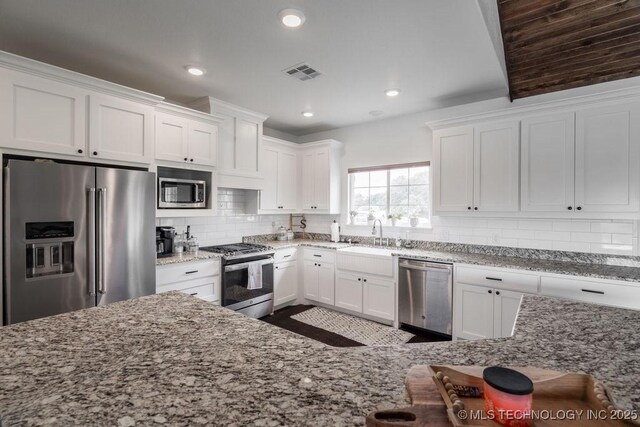 8486 Mcduffee Rd, Kingston, OK 73439 - kitchen featuring stainless steel appliances, white cabinetry, backsplash, light stone countertops, and recessed lighting