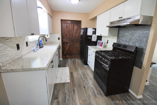 1518 E Hogner St, Tahlequah, OK 74464 - kitchen featuring stainless steel appliances, under cabinet range hood, wood finished floors, white cabinets, and backsplash