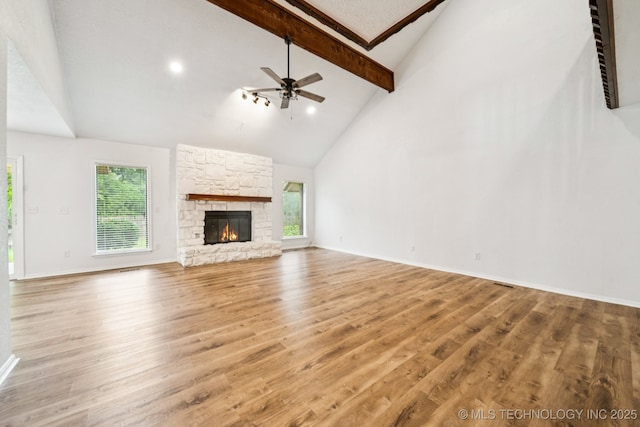 6947 S 30th W Ave, Tulsa, OK 74132 - unfurnished living room with beam ceiling, plenty of natural light, wood finished floors, a stone fireplace, and high vaulted ceiling