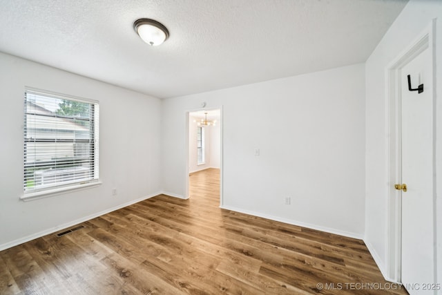 6947 S 30th W Ave, Tulsa, OK 74132 - empty room featuring a chandelier, wood finished floors, and a textured ceiling