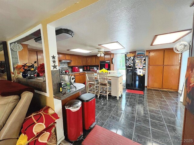 98224 S 4489th Rd, Vian, OK 74962 - kitchen with black appliances, brown cabinetry, dark countertops, a ceiling fan, and a peninsula