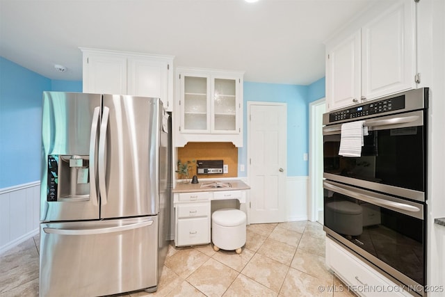 10958 S Richmond Ave, Tulsa, OK 74137 - kitchen with appliances with stainless steel finishes, a wainscoted wall, white cabinets, glass insert cabinets, and light countertops