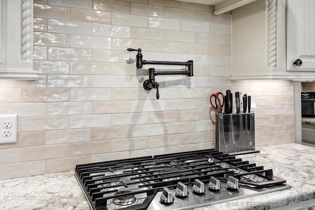 14505 E 79th St, Owasso, OK 74055 - kitchen view of pot filler, decorative backsplash, stainless steel gas cooktop, light stone countertops, and white cabinets
